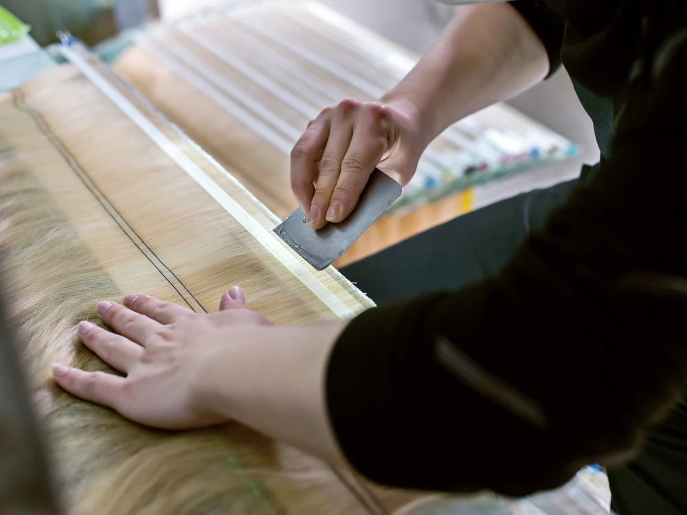 Epoche worker applying tape during human hair extension manufacturing