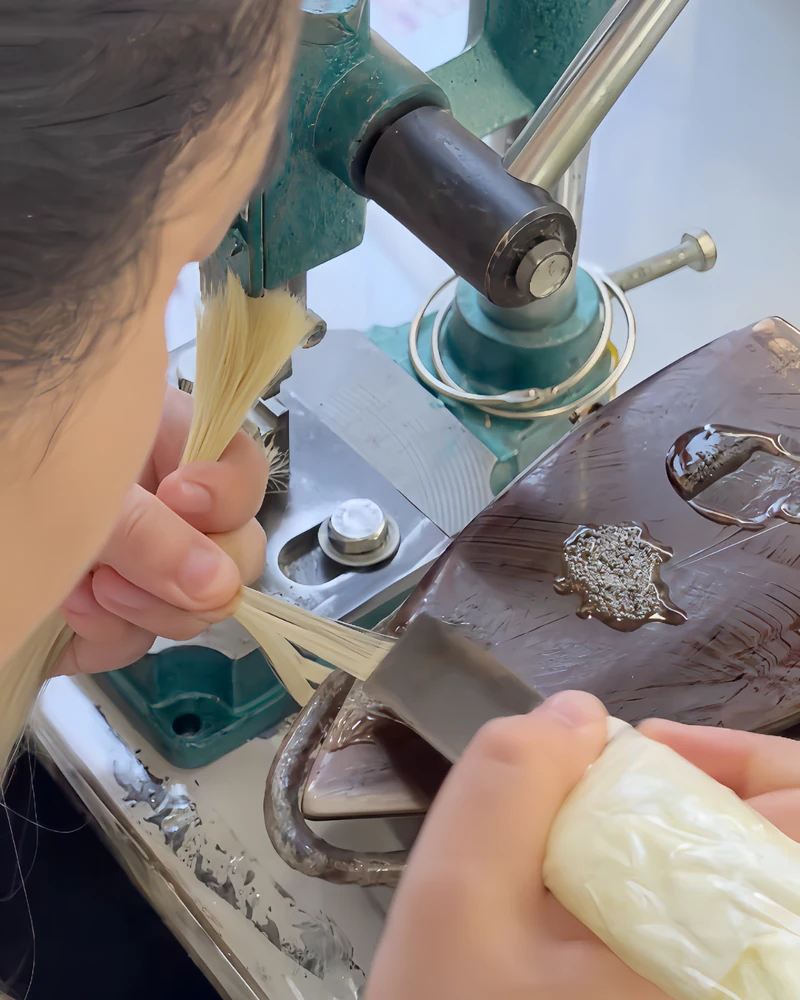 Epoche worker applying keratin bonding material while preparing human hair extension tips
