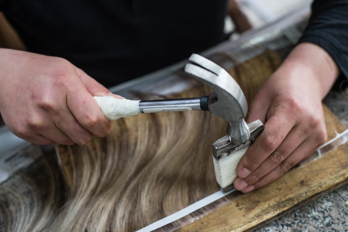 Epoche worker punching tape-in hair extension tabs during manufacturing