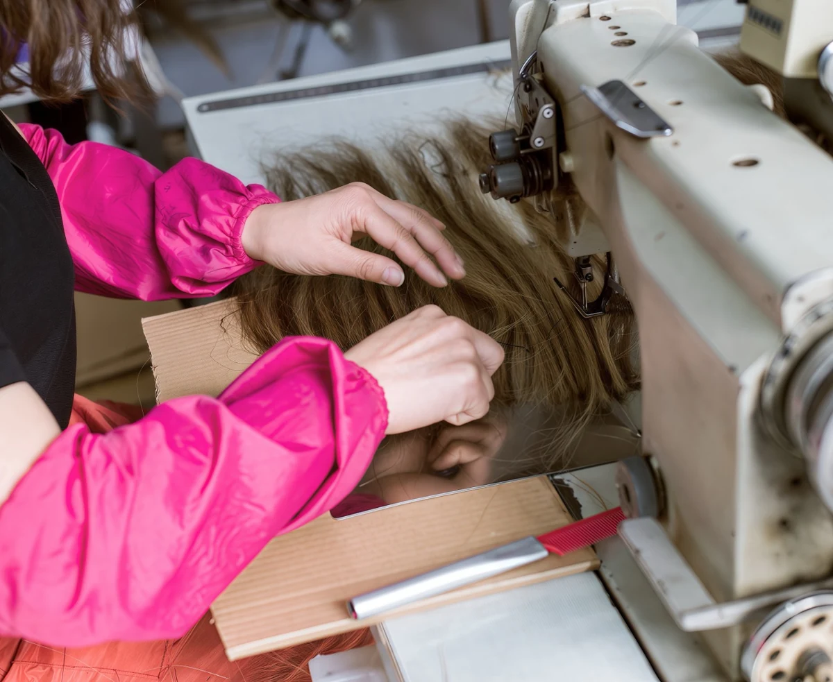 Epoche worker sewing human hair wefts on an industrial machine during weft production