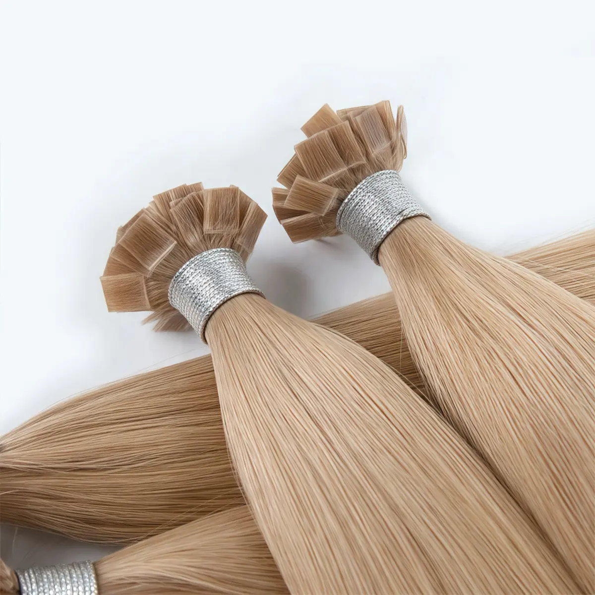 Beige blonde flat tip hair extensions with fanned keratin tips, silver bindings and overlapping straight lengths.