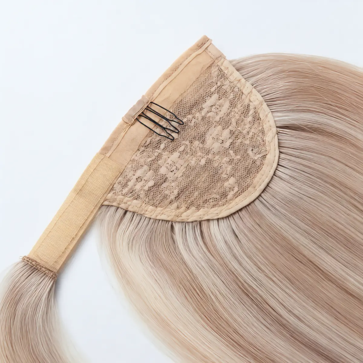 Detailed view of a ponytail extension with floral lace backing, a black attachment comb, fabric edging and a fastening tab.