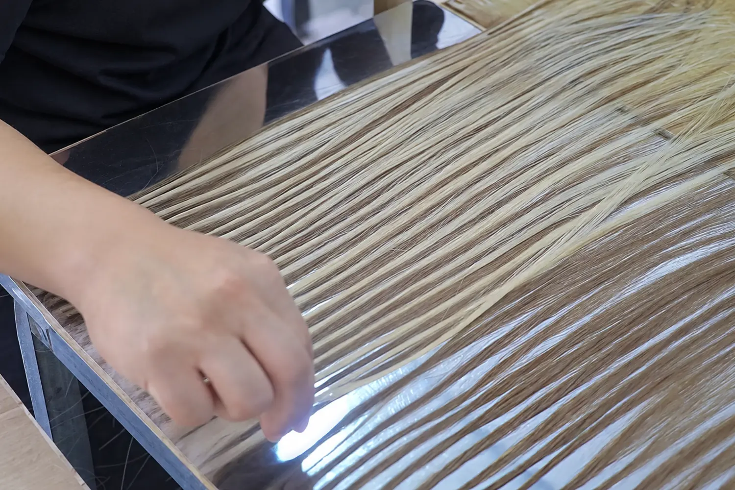 Worker arranging highlighted human hair during color development at Epoche Hair