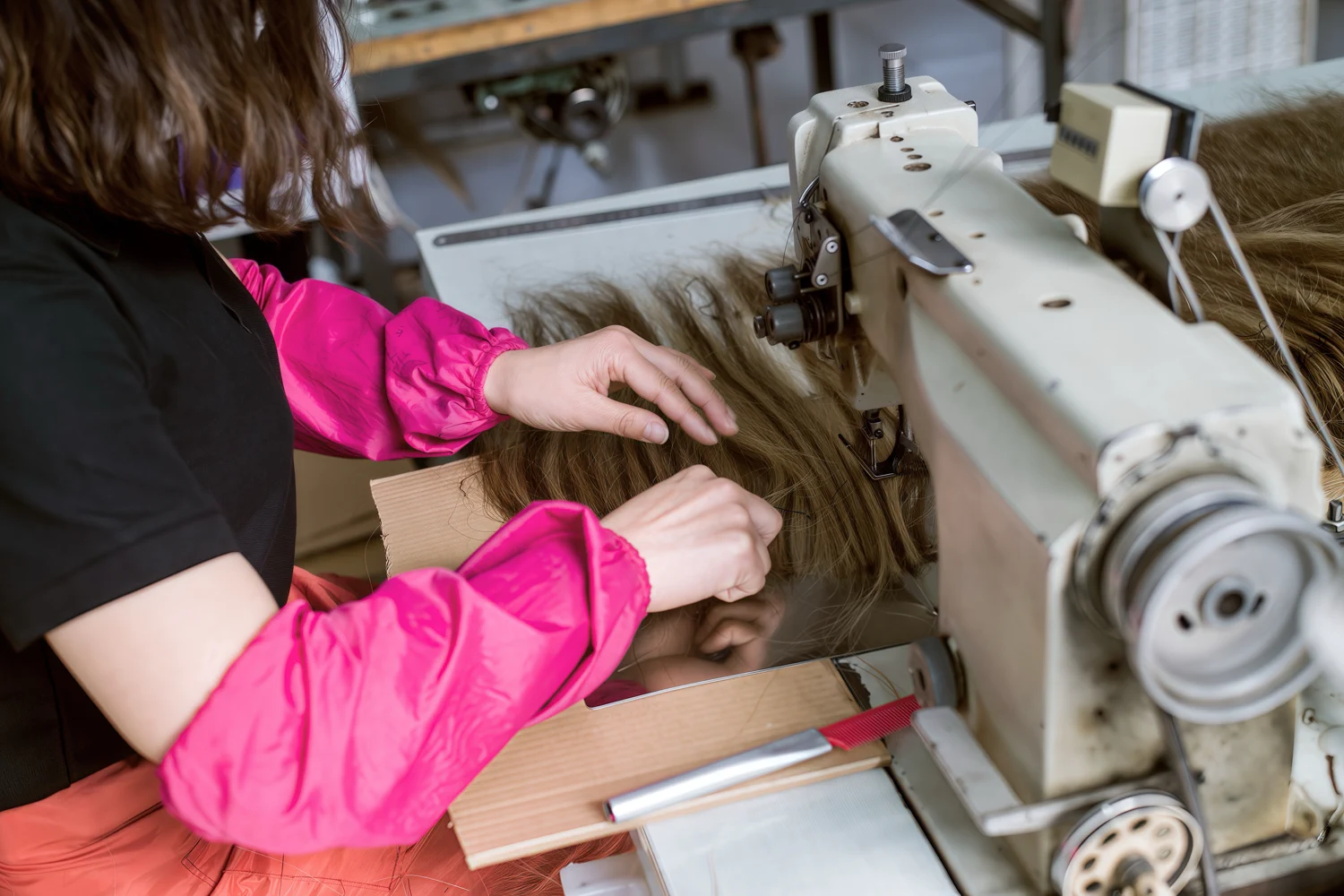 Worker sewing human hair to build a weft extension structure